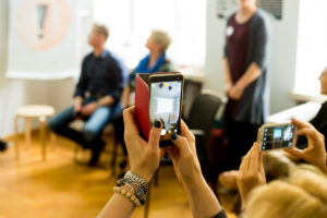 telefon trzymany w ręce, z tyłu widoczna grupa ludzi