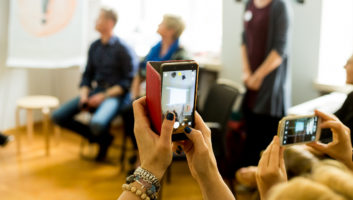 telefon trzymany w ręce, z tyłu widoczna grupa ludzi